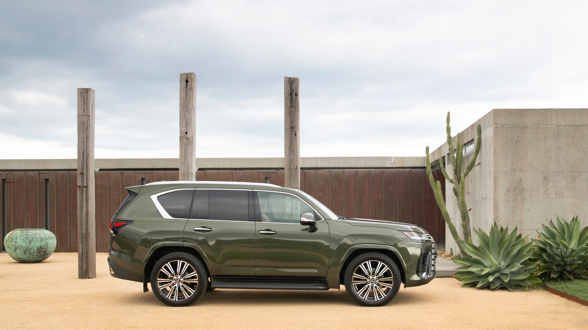 Green Lexus LX sits in a sandy driveway.